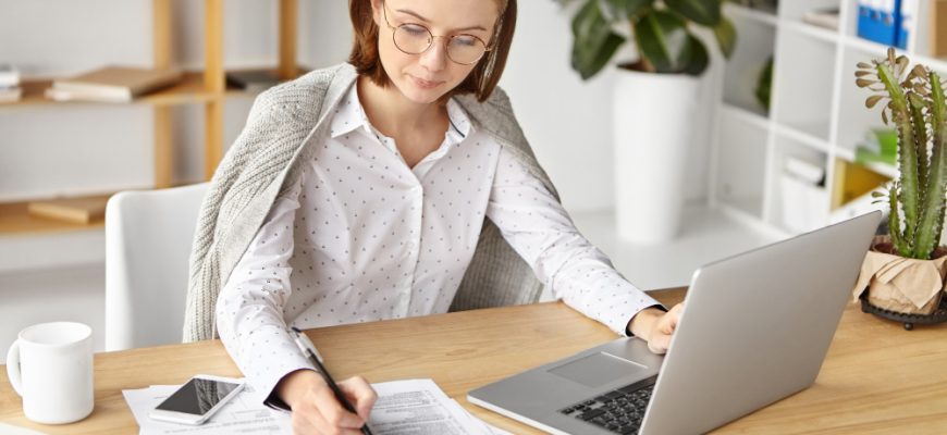 elegant businesswoman dressed formally sitting with laptop